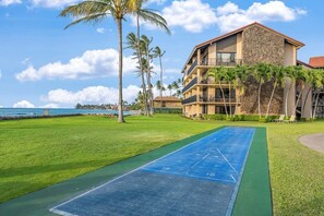 Un hôtel doté d’une piscine, d’un terrain de jeu de palet et de palmiers.