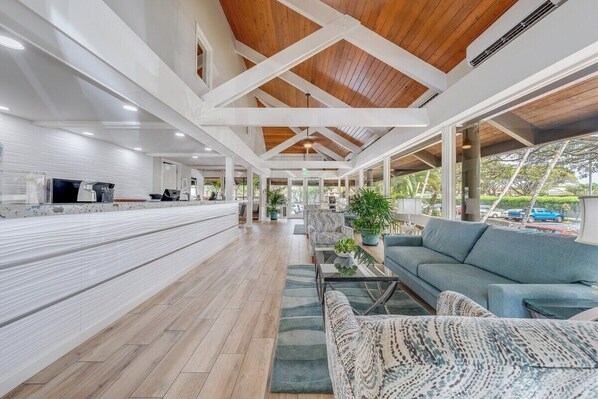 Un vaste espace intérieur doté d’un plafond en bois, d’un long comptoir avec un téléviseur et de coins salon agrémentés de plantes.
