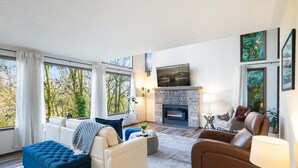 A modern living room with a fireplace, large windows, and a comfortable seating area. - Perch - Lake Forest Park Retreat (Kenmore)