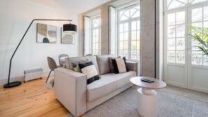 Ein modernes Wohnzimmer mit einem grauen Sofa, einem runden Couchtisch, einer Stehlampe und einer Heizung.