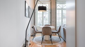 Ein Essbereich mit einem runden Tisch, vier Stühlen, einer Stehlampe und Blick durch große Fenster.
