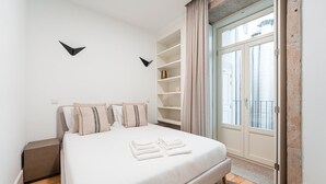 Ein modernes Schlafzimmer mit einem großen Bett, einem Einbauschrank und einem Fenster mit Vorhängen.
