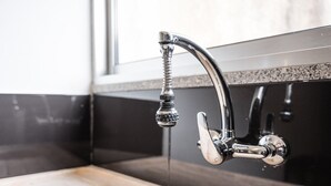 Una cocina moderna con un grifo de acero inoxidable, encimera de madera y un salpicadero negro.