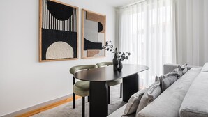 A modern living room with a dining table, two chairs, a sofa, and abstract art on the wall. - GuestReady - Urban elegance in Porto (Porto)