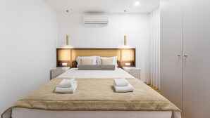 A modern hotel room with a large bed, bedside tables, an air conditioning unit, and a wardrobe. - GuestReady - Urban elegance in Porto (Porto)