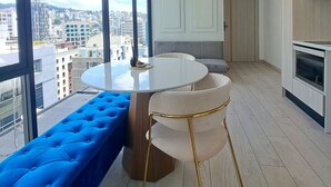 A modern kitchen with a round dining table, a blue bench, and a city view through large windows. - Luxury Penthouse Suite in La Carolina  (Quito)