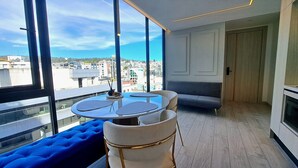 A modern room with a round table and chairs, a blue sofa, and a view of the city through large windows. - Luxury Penthouse Suite in La Carolina  (Quito)