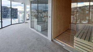A spacious balcony with a city view, large glass doors, and a wooden deck. - Luxury Penthouse Suite in La Carolina  (Quito)