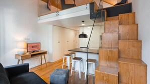 A modern interior with a wooden staircase, a desk with a computer, and a bar area. - GuestReady - Charming mezzanine near Porto (Vila Nova de Gaia)