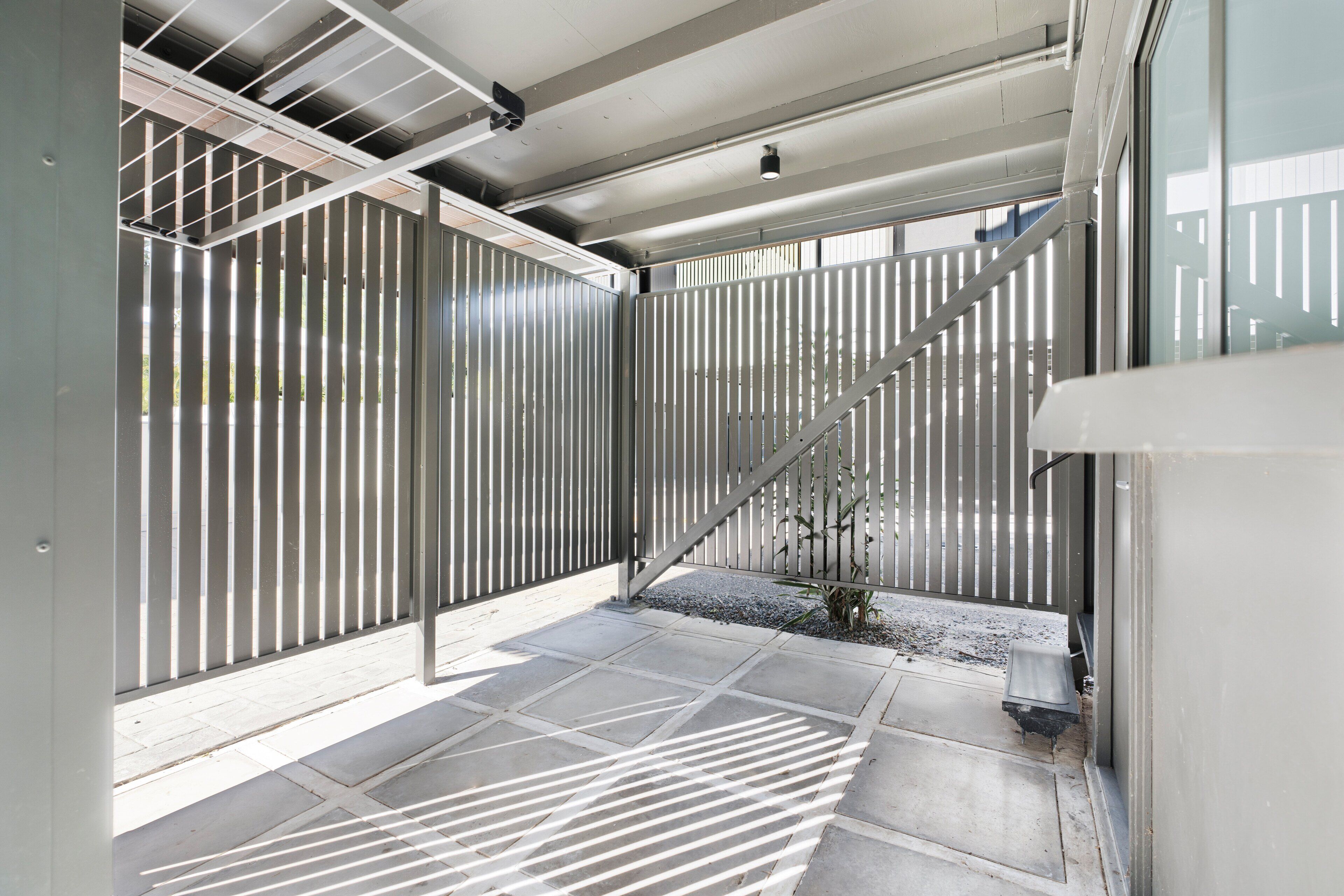 A modern building with a metal fence, a staircase, and a small plant.