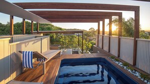 A wooden deck with a hot tub, lounge chairs, and a view of the surrounding landscape. - Hastings Villas (Noosa Heads)