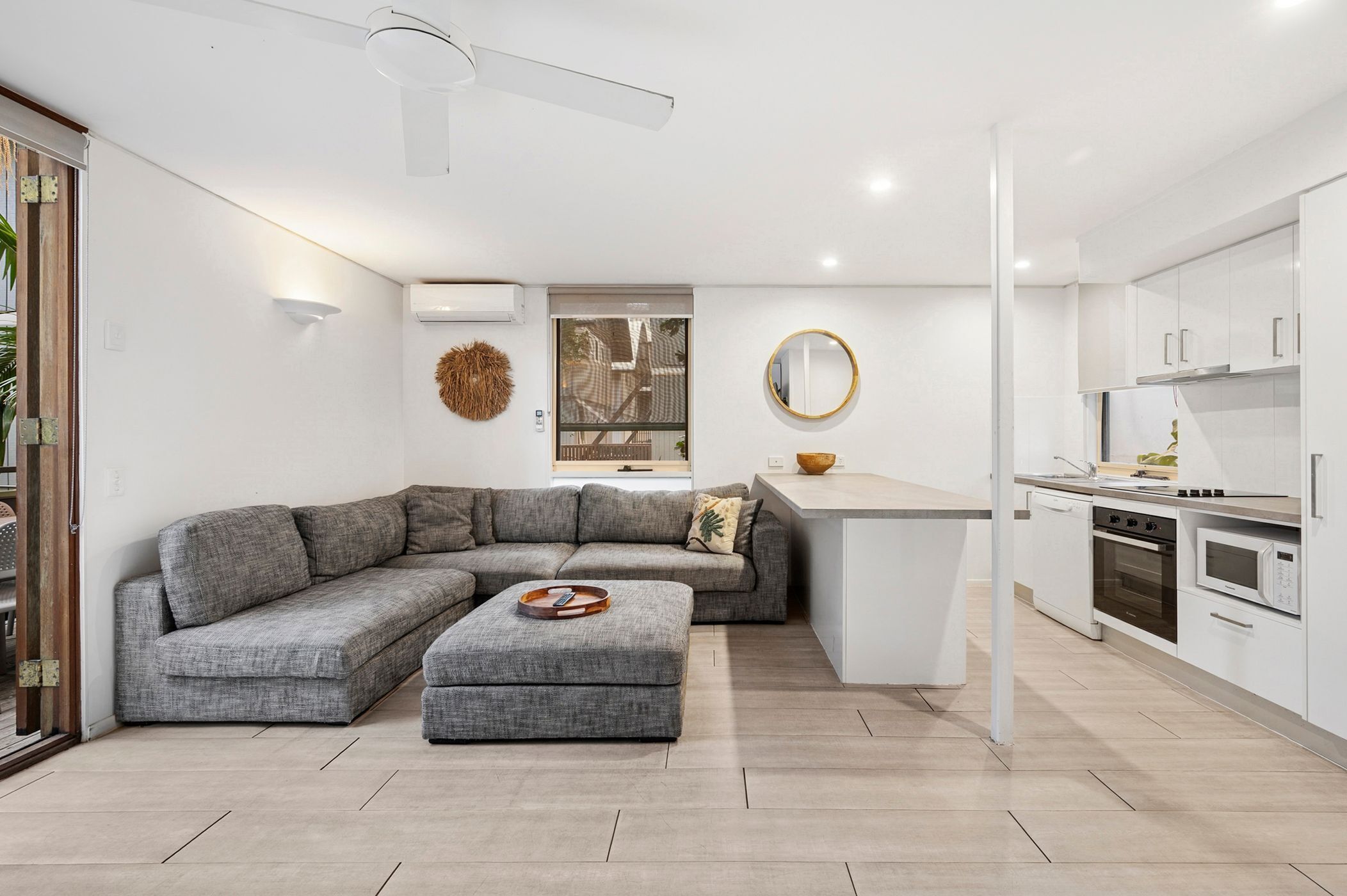 A modern kitchen with white cabinets, a built-in oven, and a microwave.
