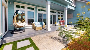 A covered patio with a hanging chair, a sofa, and a small table.