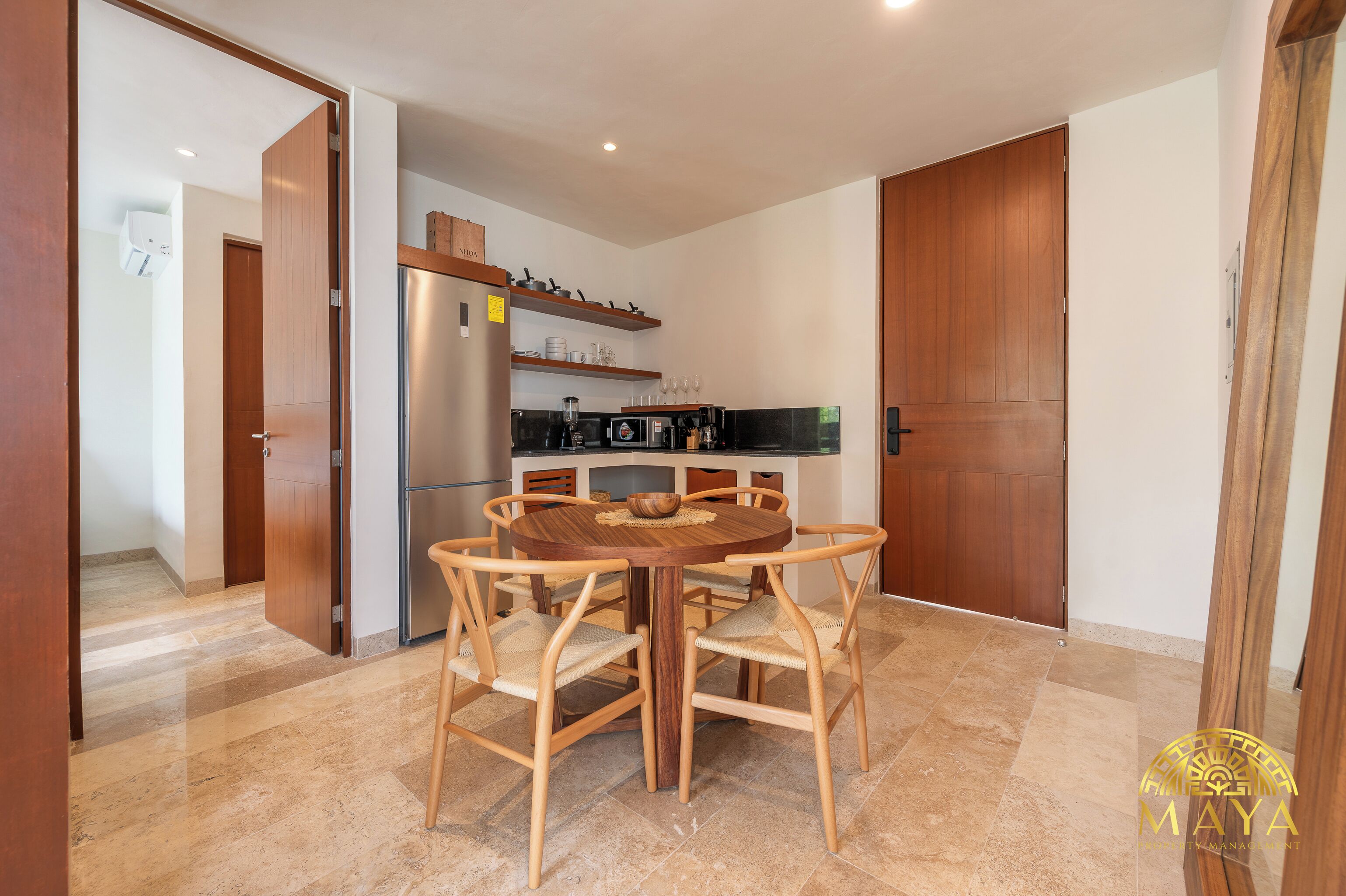 Una cucina compatta con un tavolo rotondo, sedie di legno e un frigorifero integrato.