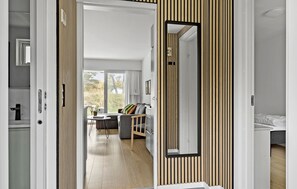 Ein modernes Interieur mit einer Wand aus Holzlamellen, einer Essecke mit Tisch und Stühlen sowie einem Bett im angrenzenden Raum.