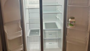 Moderni jääkaappi, jossa on kaksi ovea, pakastinosa ja erillinen lokero tuotteiden säilyttämiseen.