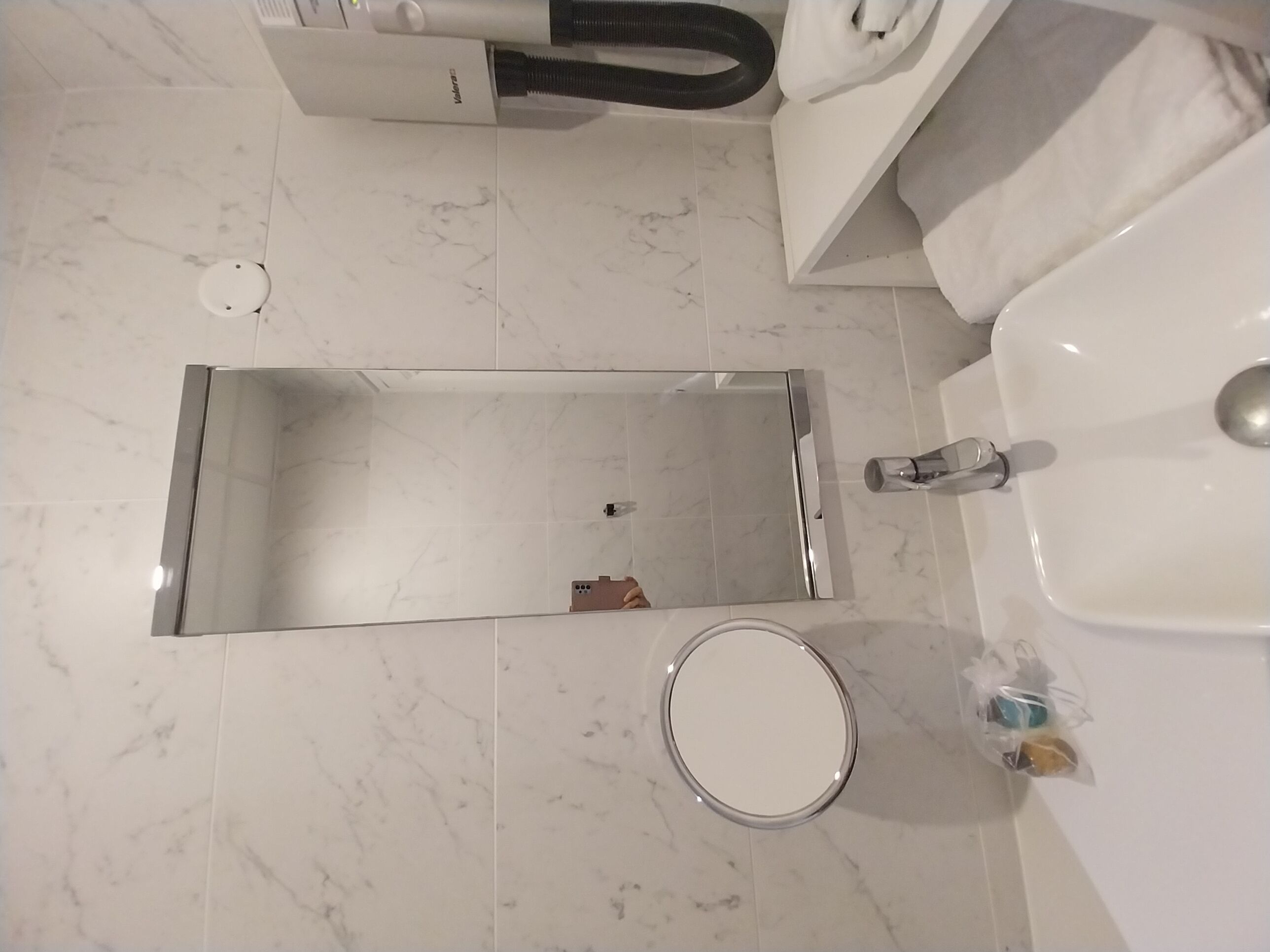 Een badkamer met een wit wastafel, een spiegel en een douche.