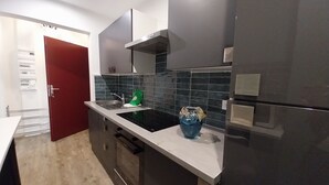 A modern kitchen with dark cabinets, a white countertop, a stainless steel sink, and a blue decorative bowl. - Apartment T2+ ( sleeps 3 ) (Bagnères de Luchon)