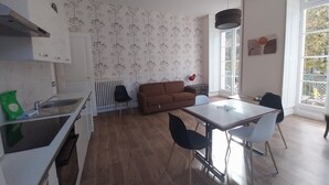 Una cocina moderna con armarios blancos, un sofá marrón y un comedor con mesa y sillas.