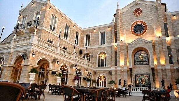 A historic building with a courtyard, outdoor seating, and a prominent clock tower.