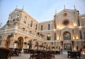 A historic building with a courtyard, outdoor seating, and a prominent clock tower. - Grandbangsaray (Sattahip)