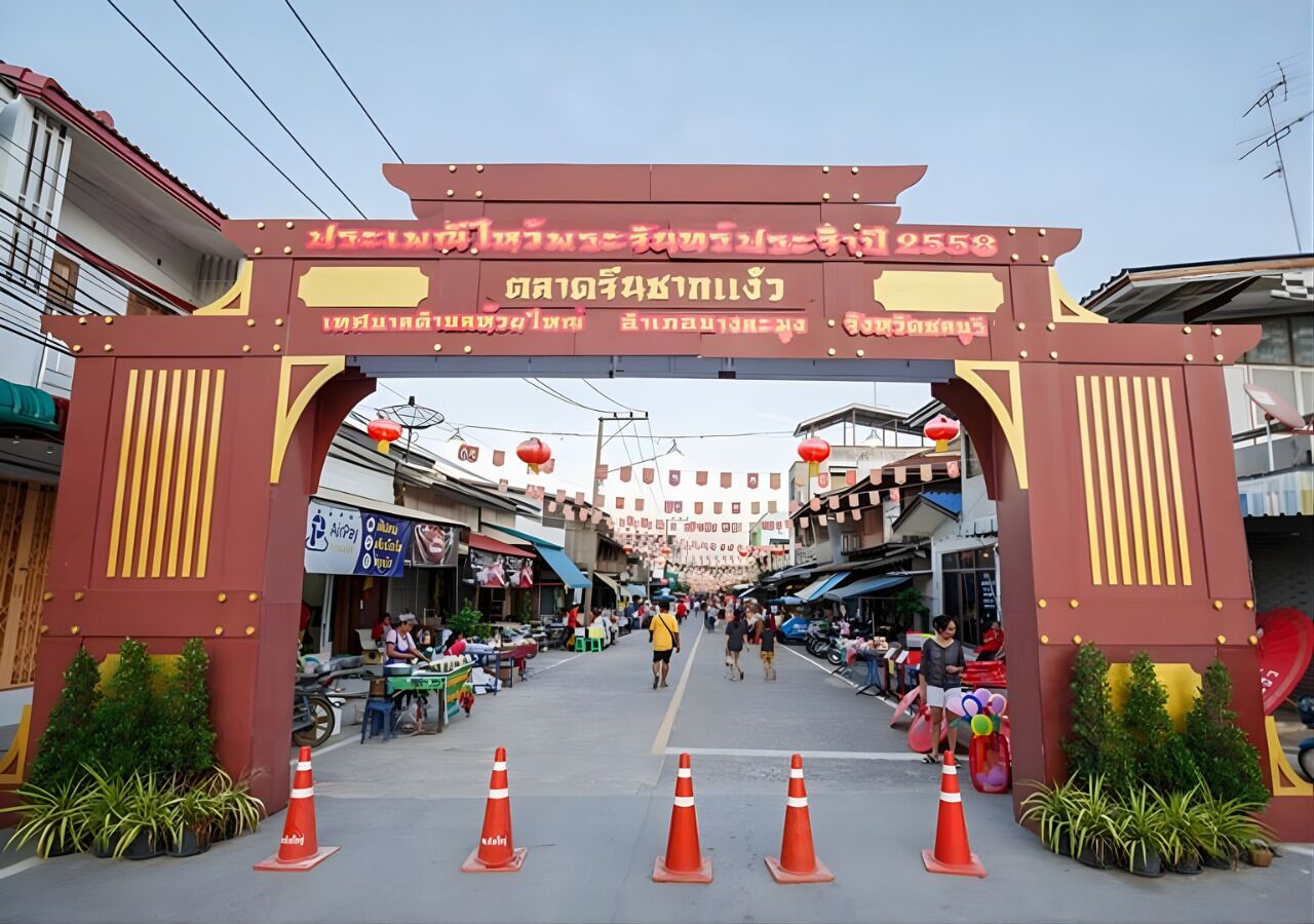 A street entrance with a large archway, potted plants, and orange traffic cones.