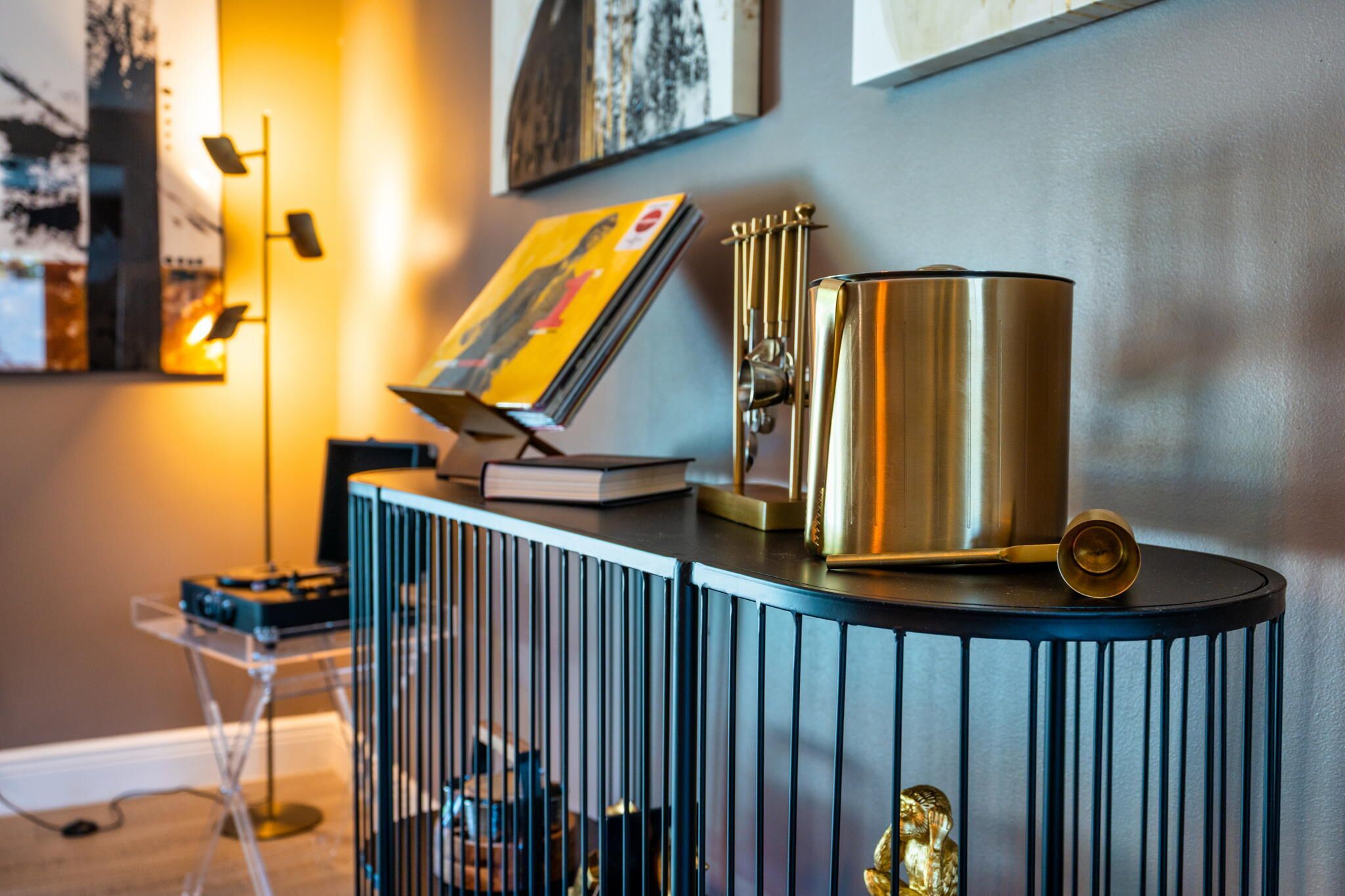 A modern room with a blue and black console table, a golden vase, and a framed picture on the wall.
