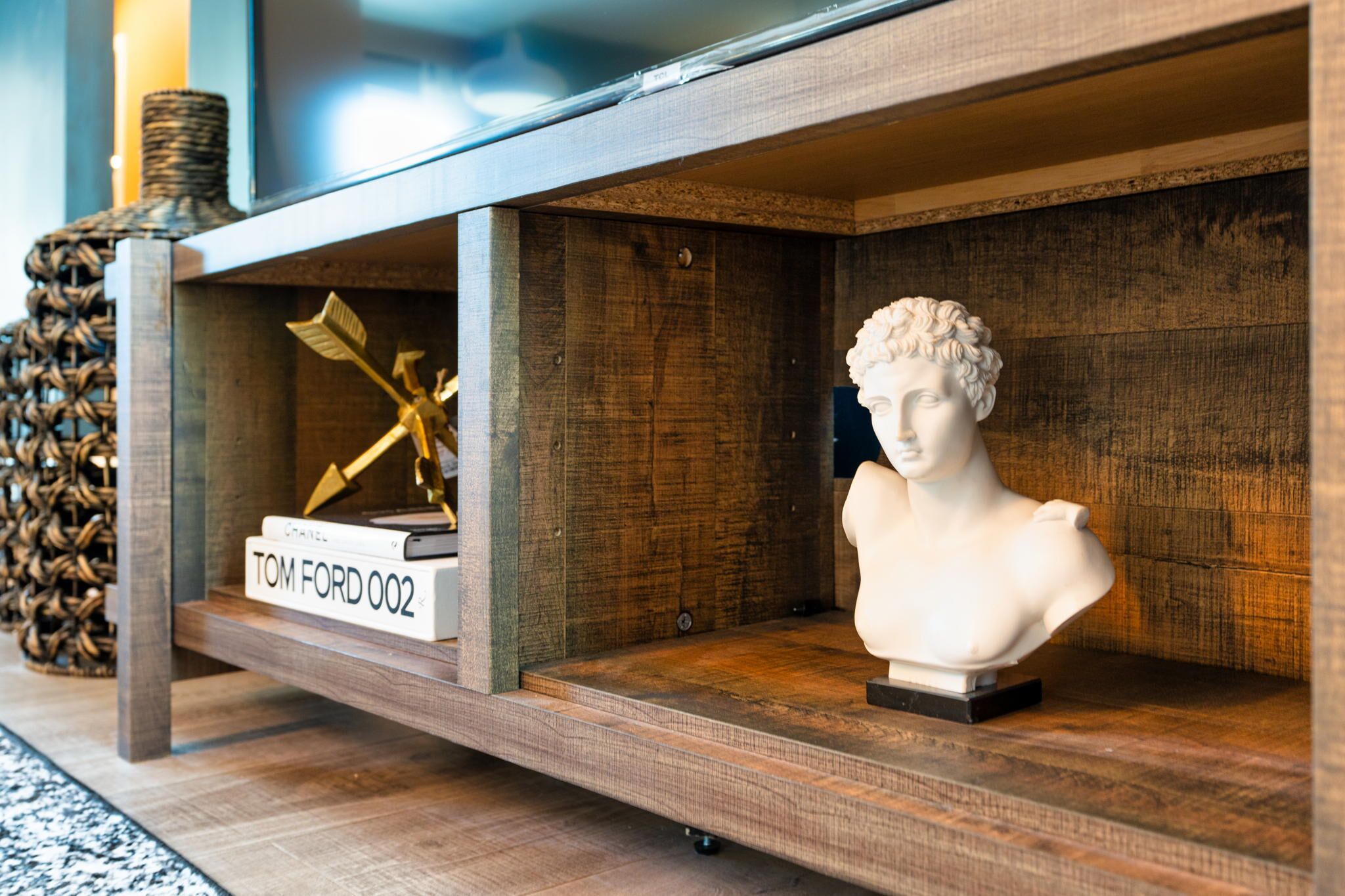 A wooden shelf with a bust sculpture and a book titled "TOM FORD 002".