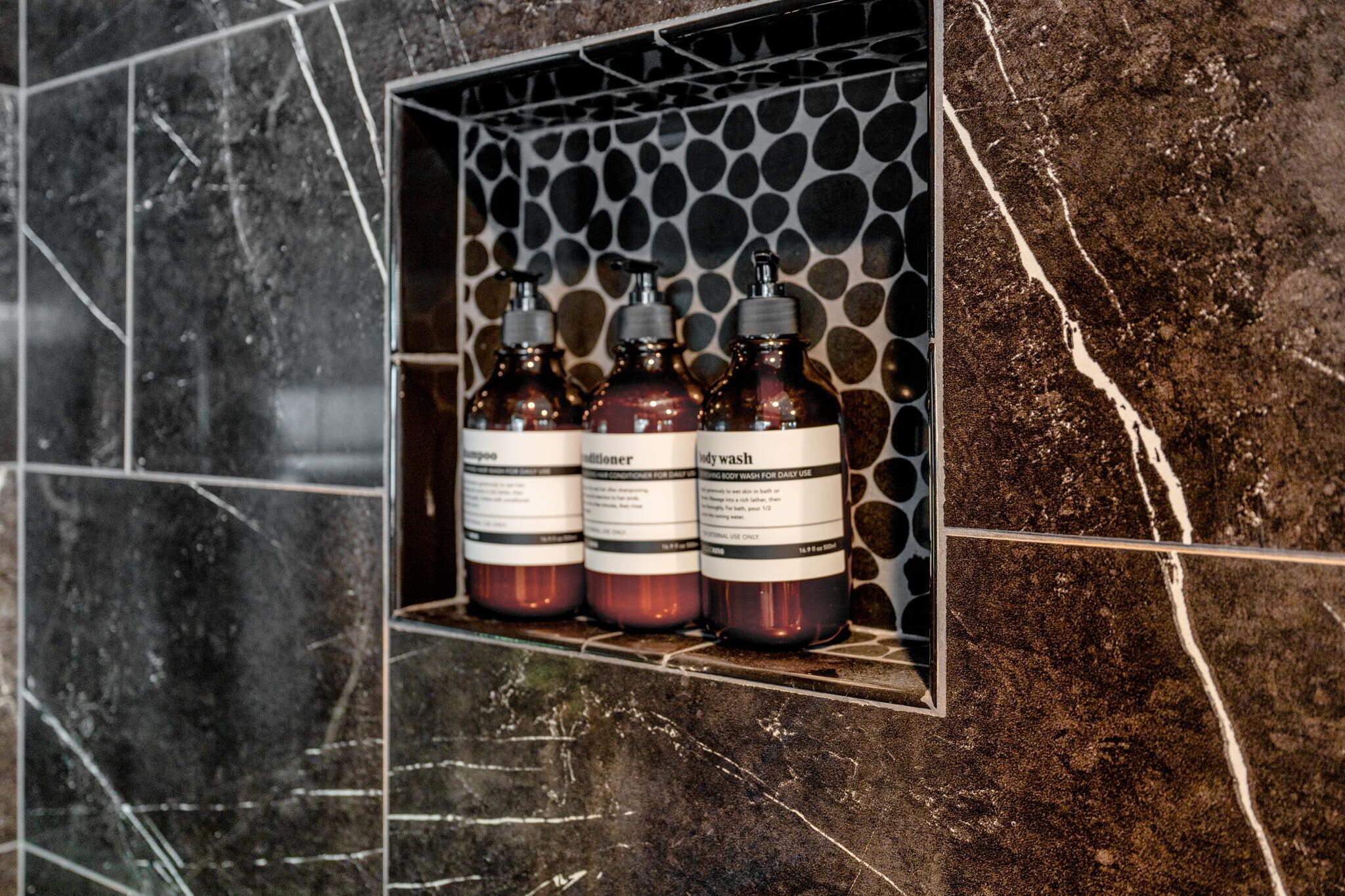 A bathroom shelf with three bottles of body wash.