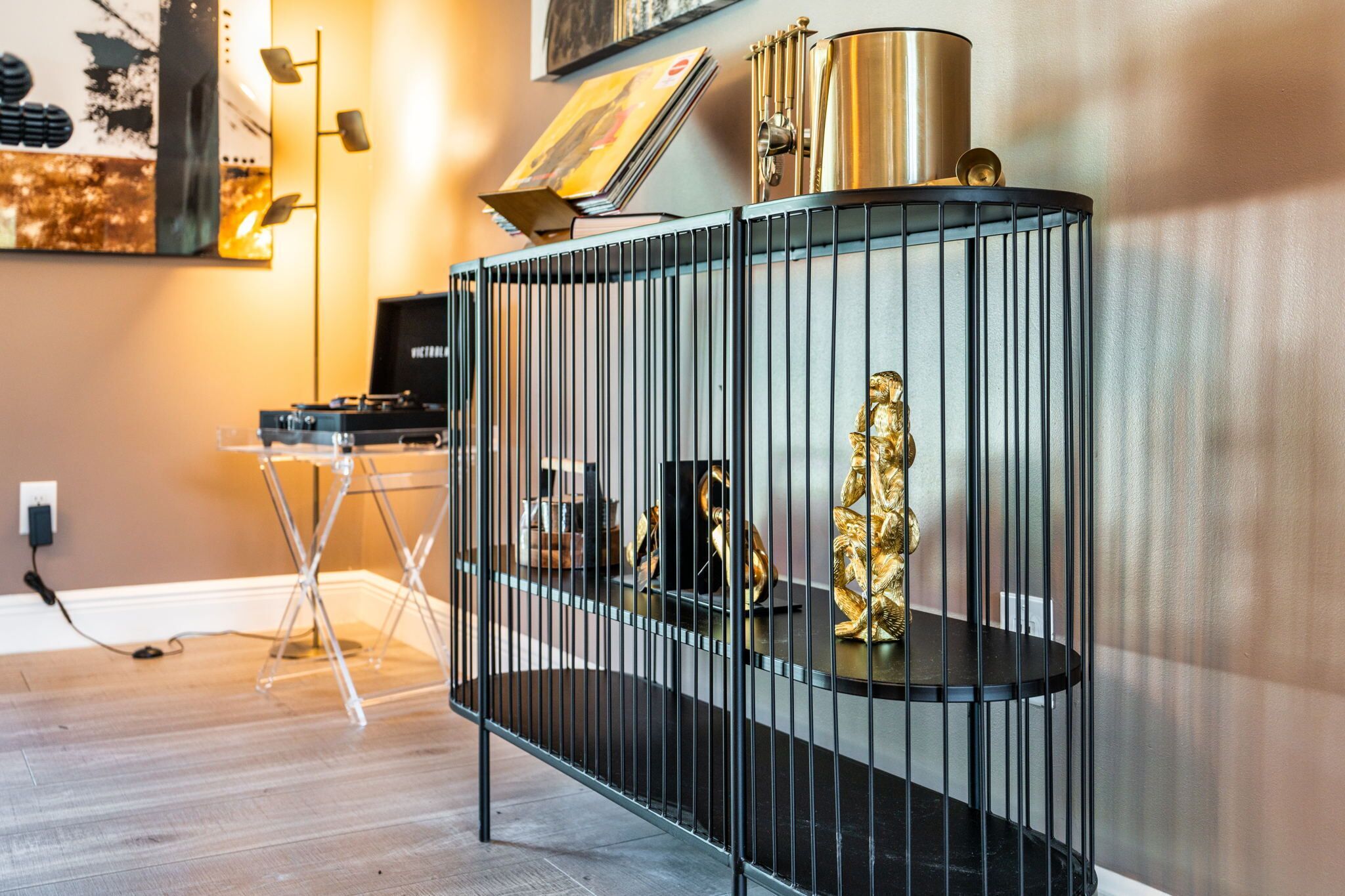 Een modern interieur met een zwarte metalen schapunit, een kleine tafel en een gouden beeldje.