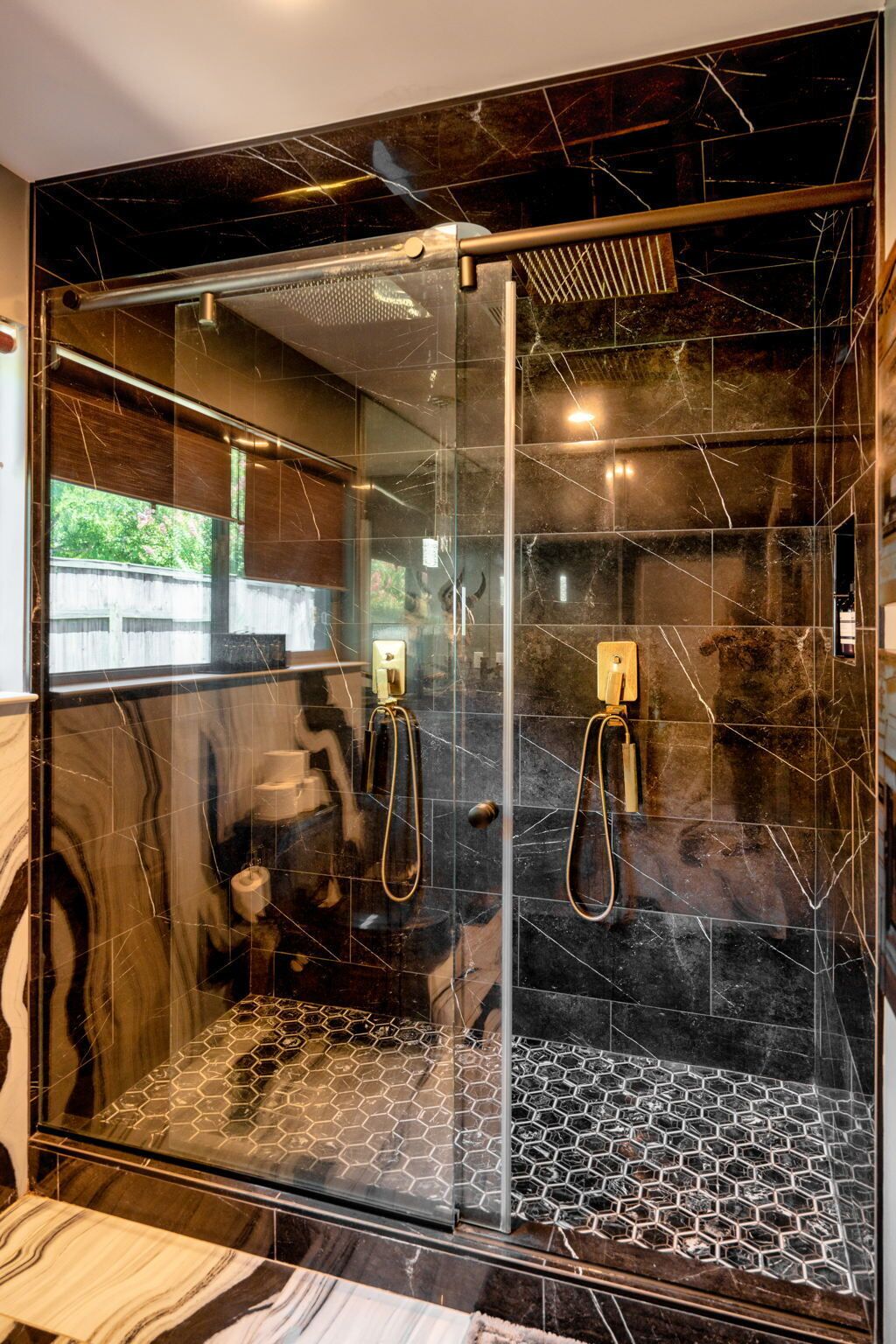 Un bagno moderno con cabina doccia in vetro, piastrelle in marmo e un motivo esagonale sul pavimento.