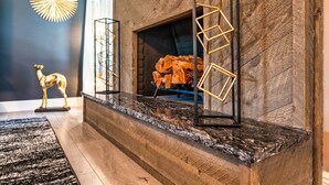 A modern living room with a fireplace, wooden flooring, and decorative elements like a golden giraffe statue and geometric wall art. - Sinatra Fun 5BD Home Huge Pool Game Room (Round Rock)
