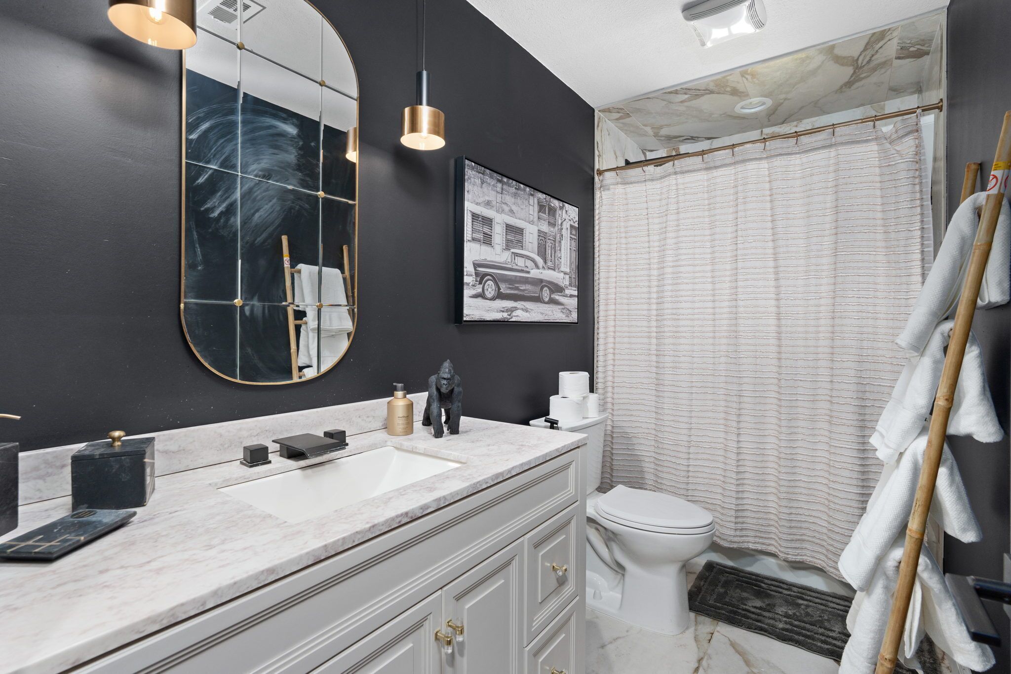 A modern bathroom with a large mirror, a sink, and a toilet.