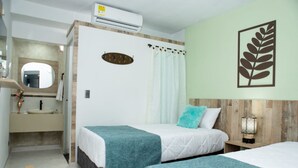 A hotel room with two beds, a bathroom with a sink and mirror, and a wall-mounted air conditioner. - ArisSha Boutique Hotel (Cali)