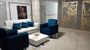 A modern living room with a white sofa, two blue armchairs, and a white coffee table. - ArisSha Boutique Hotel (Cali)
