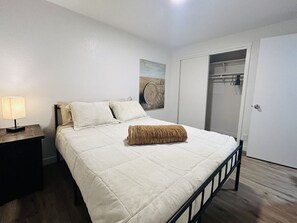 A bedroom with a bed, a nightstand, a lamp, a closet, and a door. - Giddy Up Getaway in Nampa (Nampa)