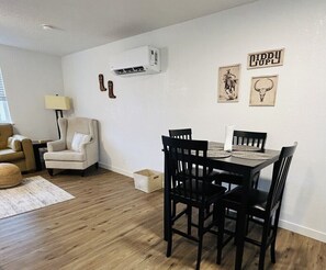 A dining area with a wooden table and black chairs, a beige armchair, a lamp, and wall decorations including a bull's head and a sign. - Giddy Up Getaway in Nampa (Nampa)
