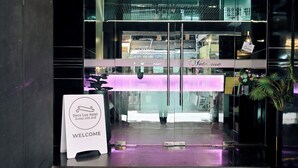 The entrance of Deco Lux Hotel with a 'Welcome' sign, glass doors, and a reception desk. - Deco Lux Hotel (Bangkok)