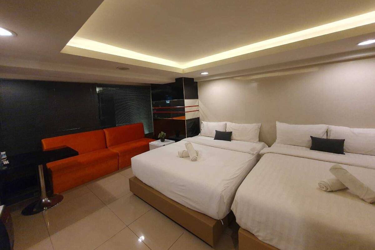A modern hotel room with a large bed, a sofa, and a small table.