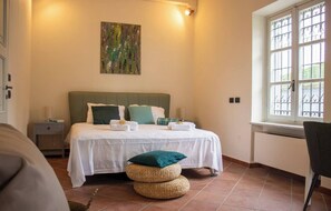 A neatly arranged bedroom with a bed, bedside tables, a window with bars, and a painting on the wall. - Impressive: Villa Magna with pool and park - Langhe wine region (Govone)