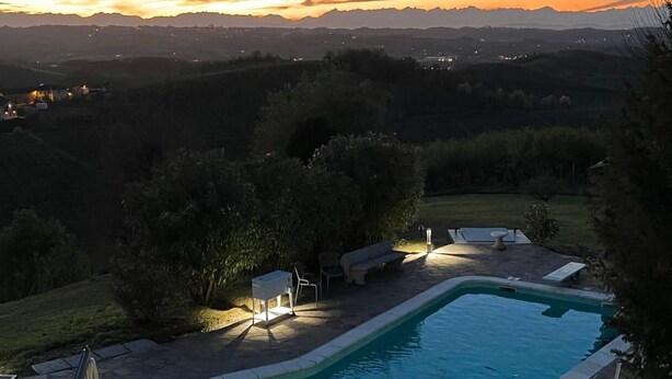 Una piscina amb gandules i una taula, envoltada de vegetació i amb vistes a muntanyes llunyanes.