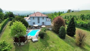 Una casa espaiosa amb piscina, envoltada de vegetació exuberant i turons.
