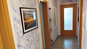 Un couloir doté d’un plancher en bois, de murs violets à texture et d’un tableau encadré.
