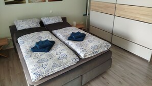 Un lit double avec une literie à motifs, une table de chevet en bois, une lampe de chevet et une armoire à porte coulissante.