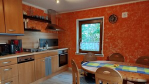 Une cuisine avec des meubles en bois, un lave-vaisselle, une cuisinière et une fenêtre donnant sur un paysage verdoyant.