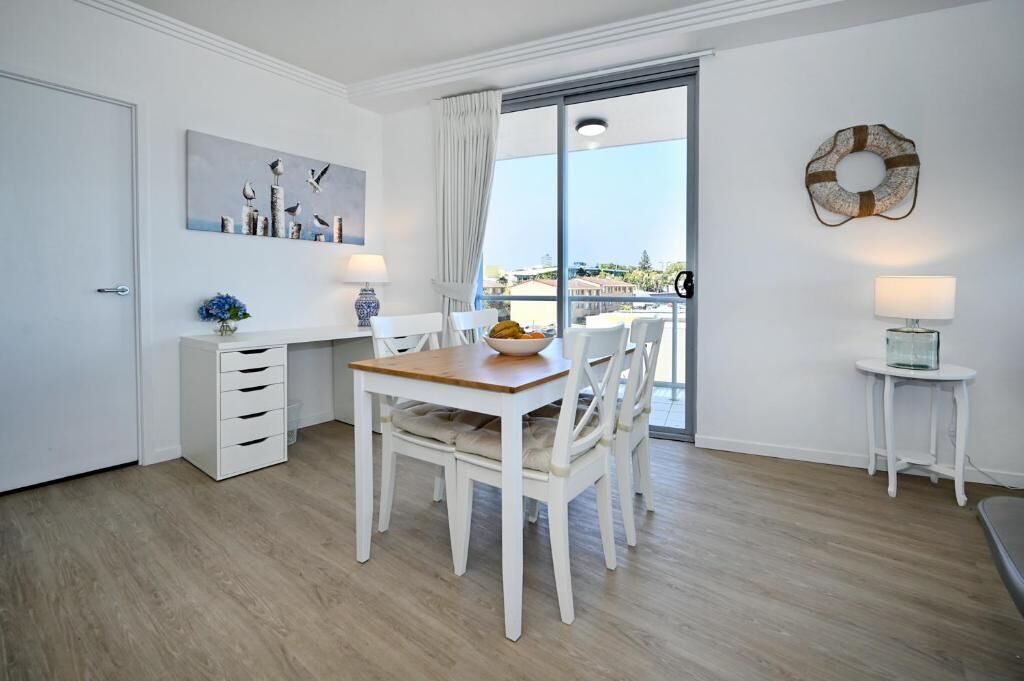Una habitación moderna y minimalista con una mesa de comedor, sillas, un mueble pequeño y vistas a través de un ventanal.