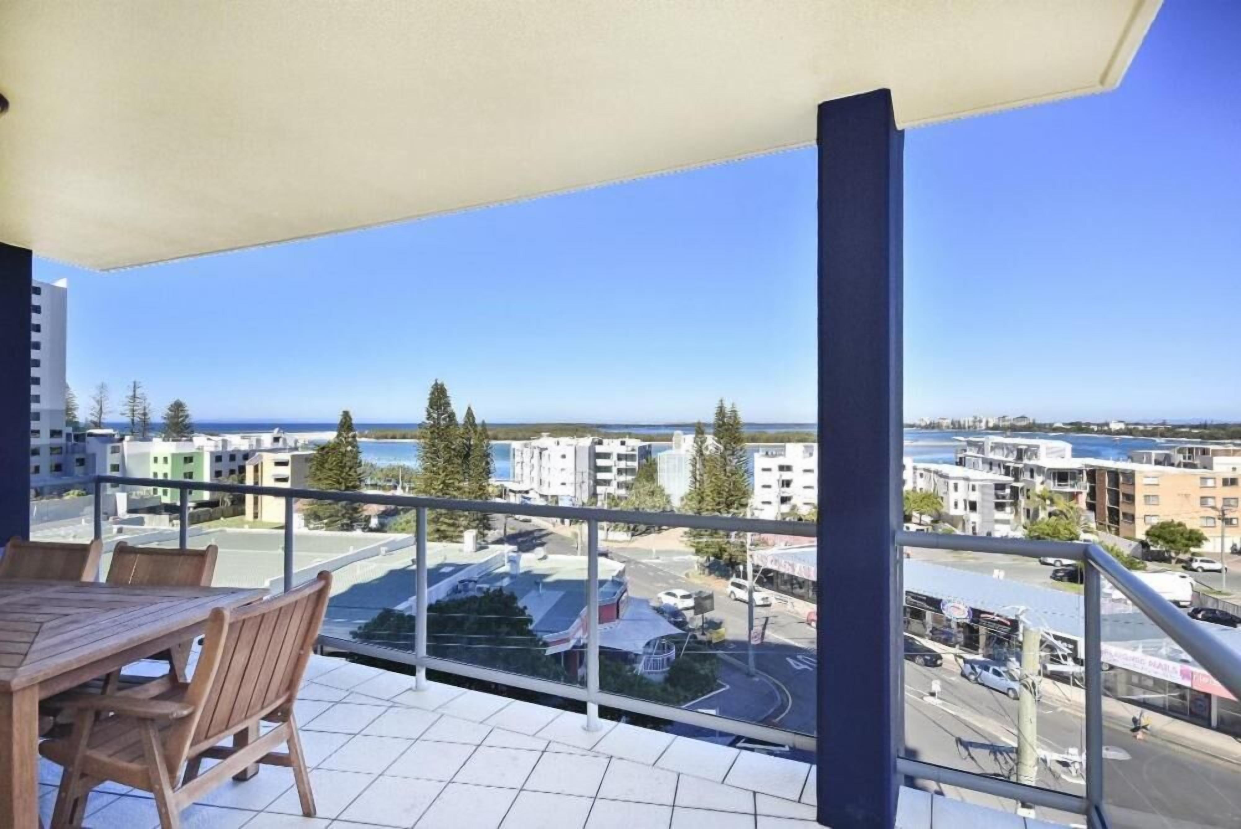 A balcony with a view of a cityscape and the sea.