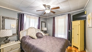 Ein Schlafzimmer mit Bett, Nachttischen, Deckenventilator und Kleiderschrank.