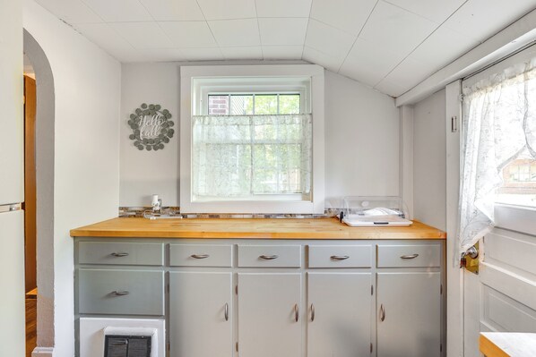 Una cocina con ventana, encimera de madera y armarios grises claros.