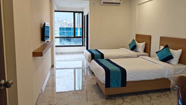 A hotel room with two beds, a ceiling fan, an air conditioning unit, and a television on a shelf. - Hotel Iris Executive (Paud)
